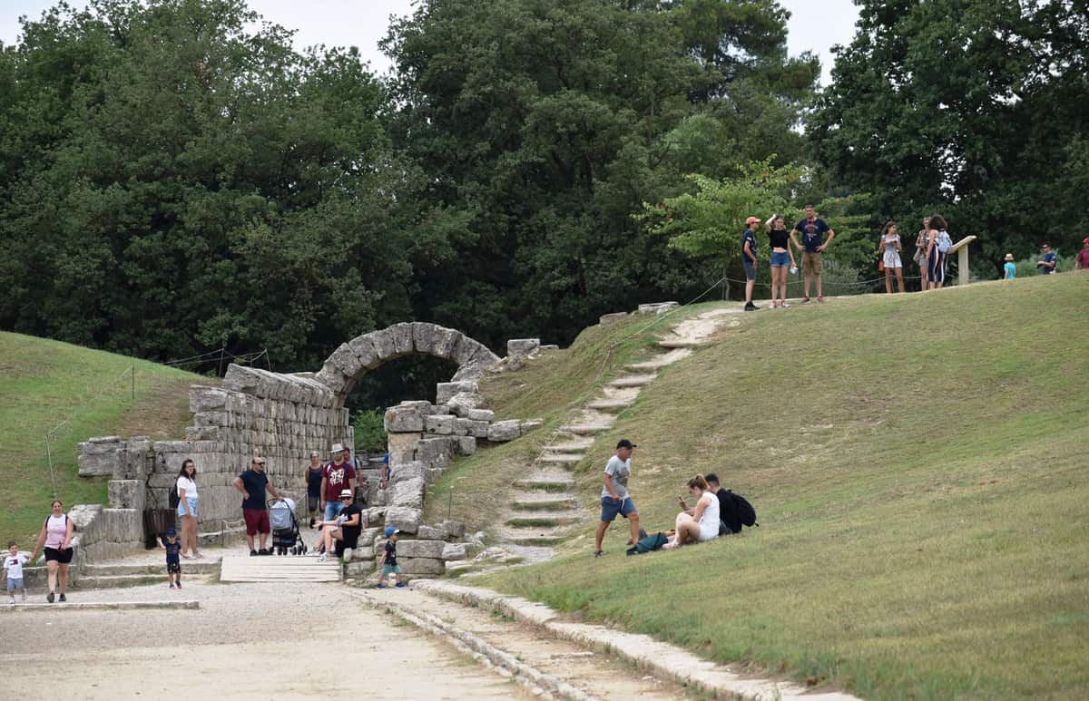 An ancient Olympia tour enters the stadium through its vaulted stone passage