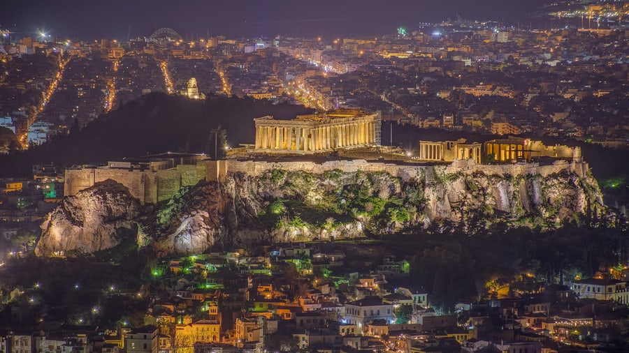 An Athens night tour looks across the lit Acropolis to the lights of the city from the hill of Lycabettus