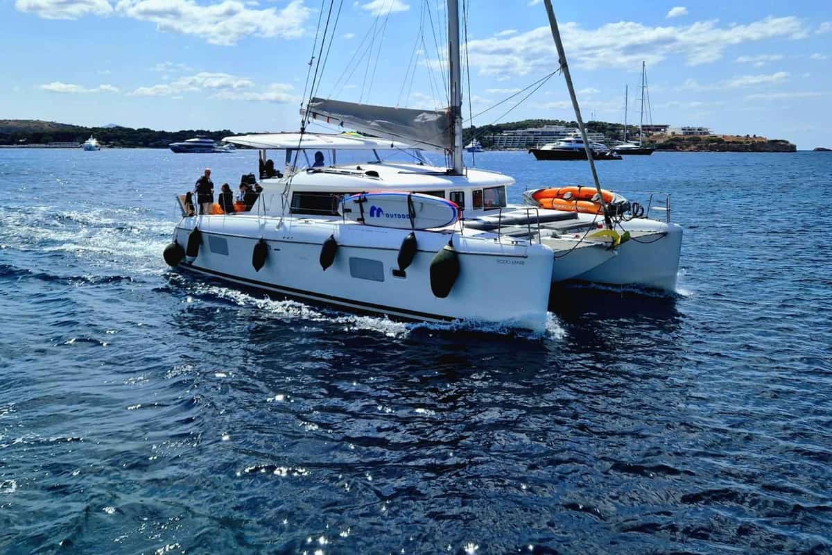 An Athens Riviera cruise sails a white catamaran with guests on deck across deep blue water off the Attica coast