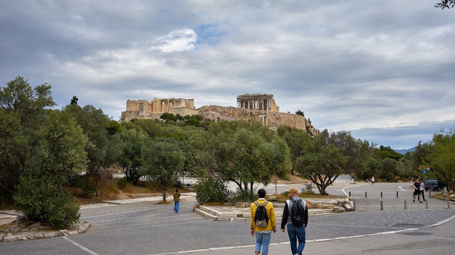 An Athens segway tour rides the pedestrian street of Dionysiou Areopagitou with the Acropolis above the trees