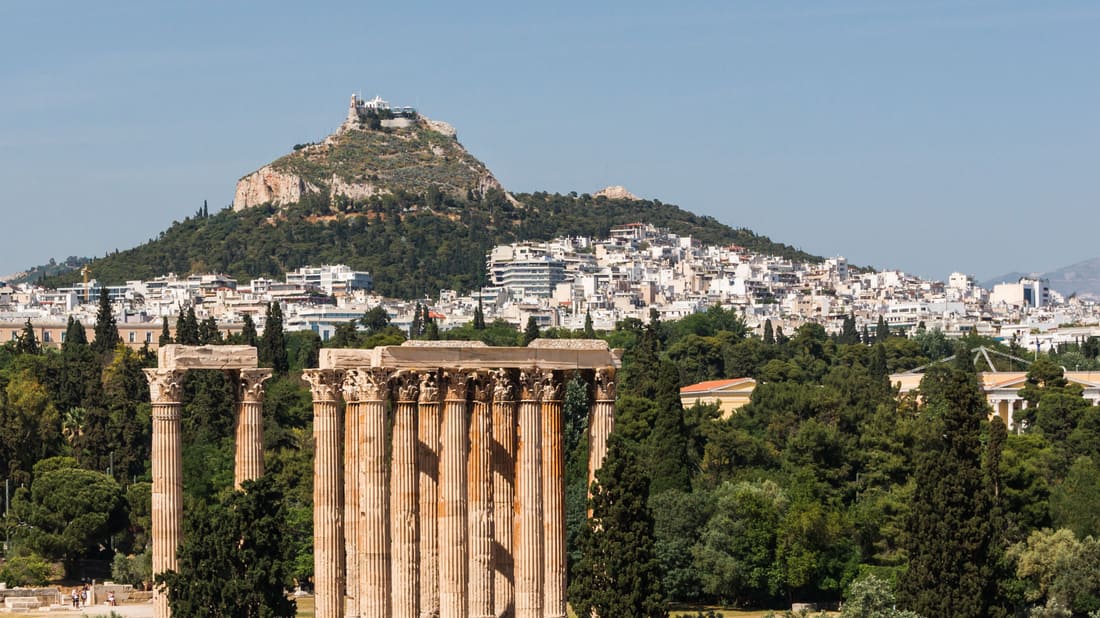 An Athens shore excursion passes the Temple of Olympian Zeus, with the hill of Lycabettus rising behind