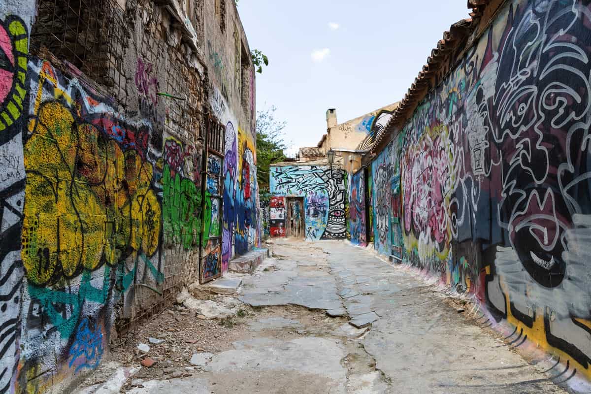 An Athens street art tour walks a narrow lane where every wall is covered in graffiti and painted murals