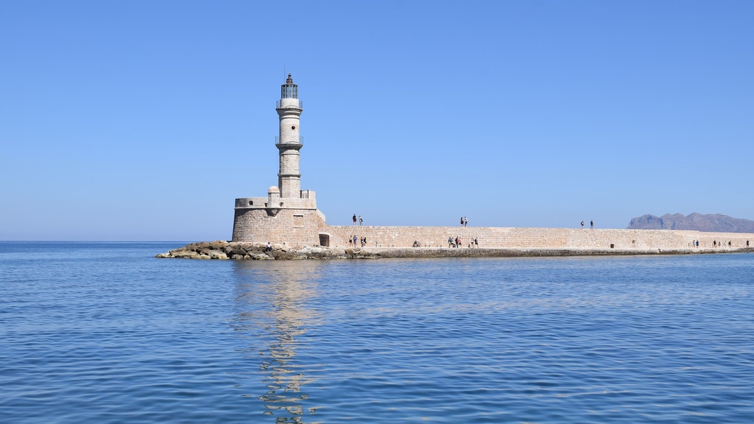 A Chania boat trip passes the Venetian lighthouse at the entrance of the old harbour of Chania
