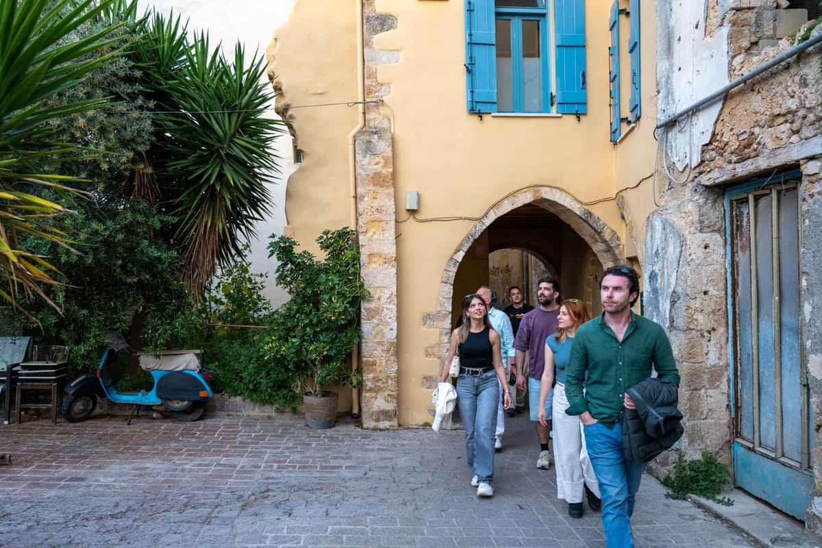 A Chania walking tour group steps out of a stone archway into a cobbled square in the old town of Chania