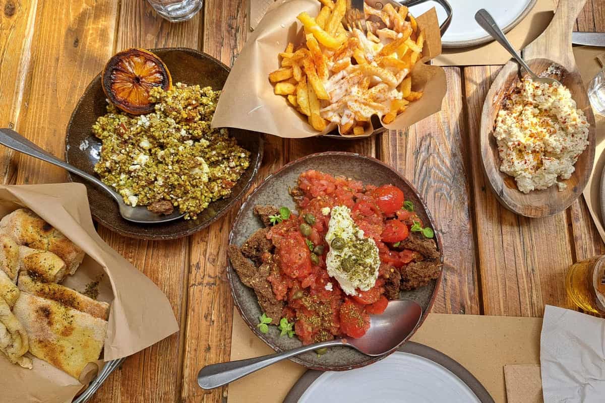 A Corfu cooking class ends at a table of Greek dishes: dakos salad, a cheese spread, a bean dish and fried potatoes