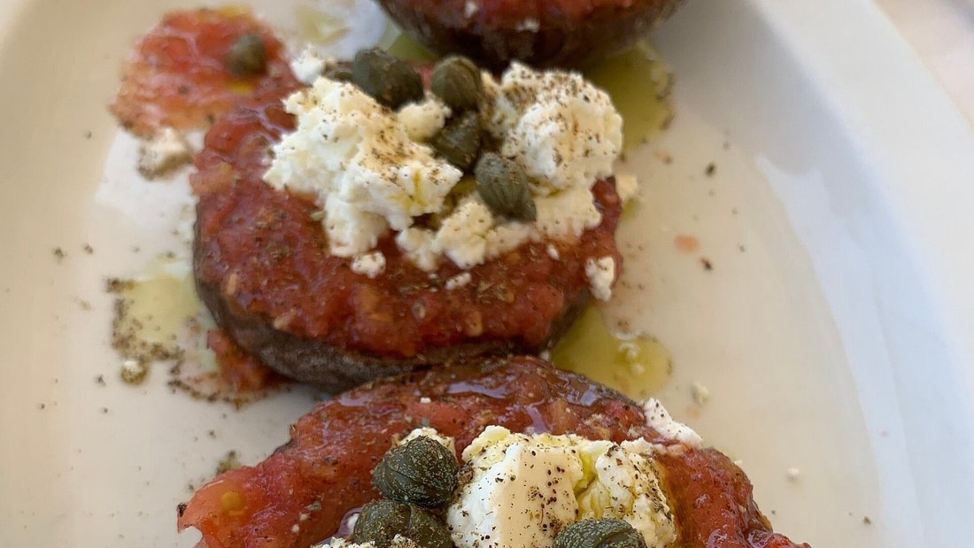 A Crete cooking class prepares dakos, barley rusks topped with grated tomato, soft cheese, capers and olive oil