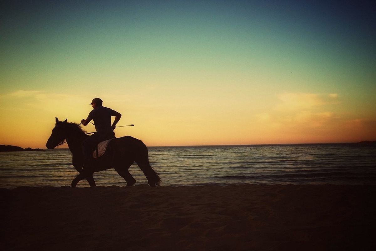 Crete horse riding at sunset: a rider canters along the beach at Chania as the sun goes down over the sea