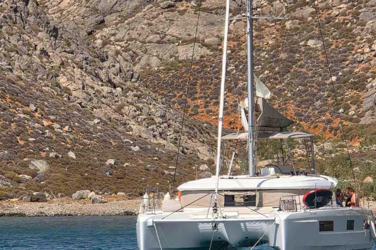 Heraklion boat trip sailing catamaran anchored in clear water below the rocky slopes of a Dia island cove