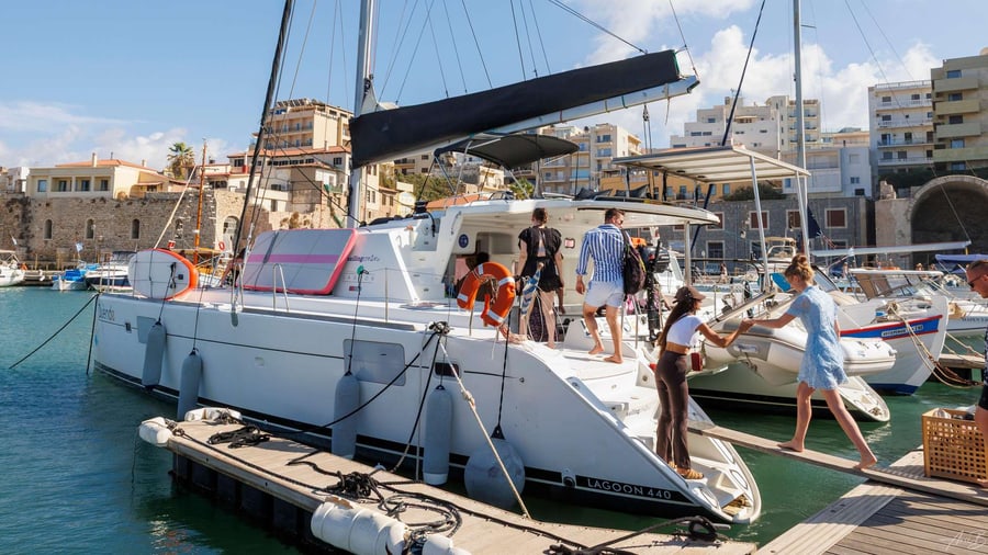 Passengers board a sailing catamaran moored in the old Venetian harbour before a Heraklion sailing tour