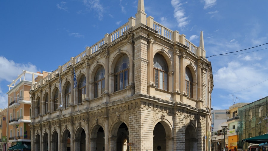 A Heraklion tour stops at the arcaded Venetian Loggia beside Lions Square under a blue sky