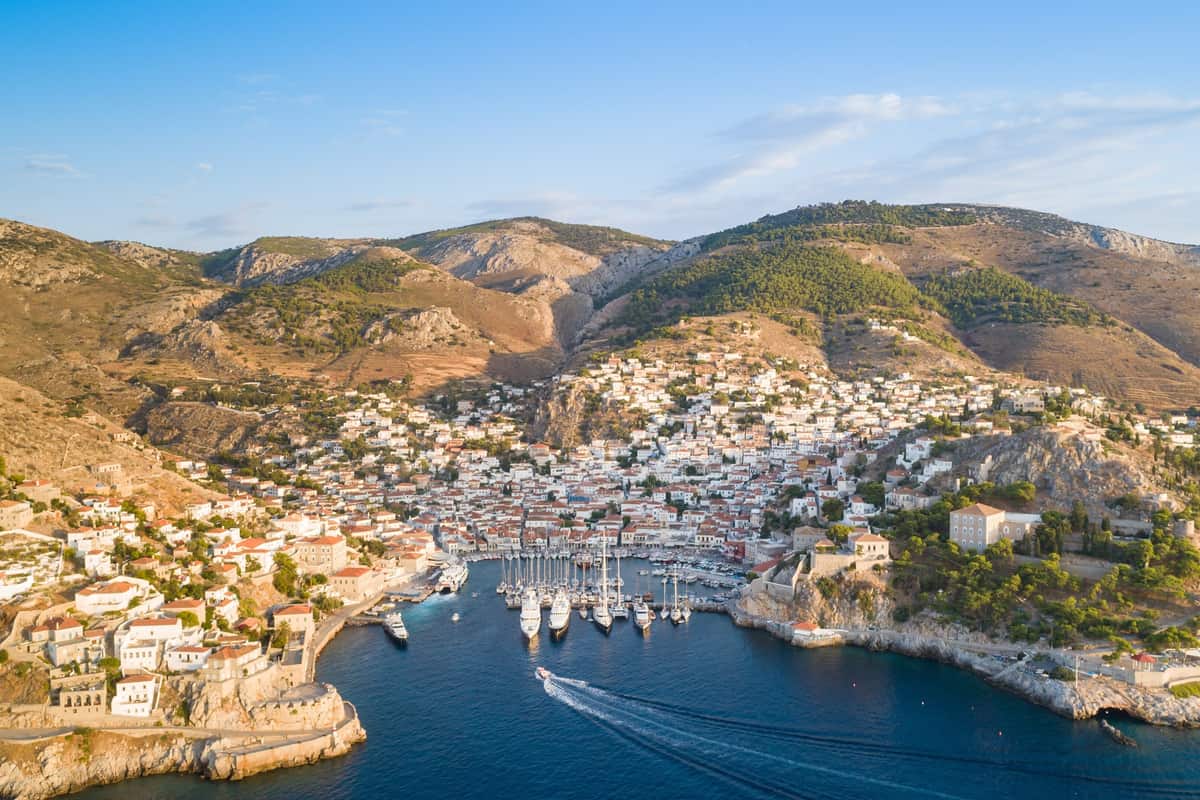 A Hydra day trip arrives at the horseshoe harbour, where stone houses climb the hills above the yachts