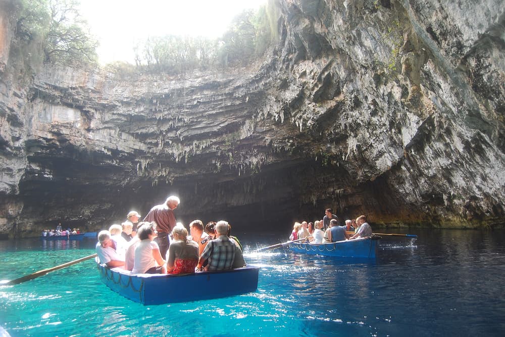 A Kefalonia boat tour visitor rows across the blue cave lake of Melissani