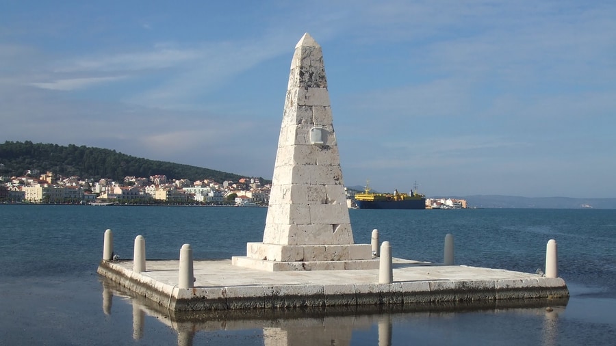 A Kefalonia island tour in Argostoli passes the stone obelisk in the bay, with the town across the water