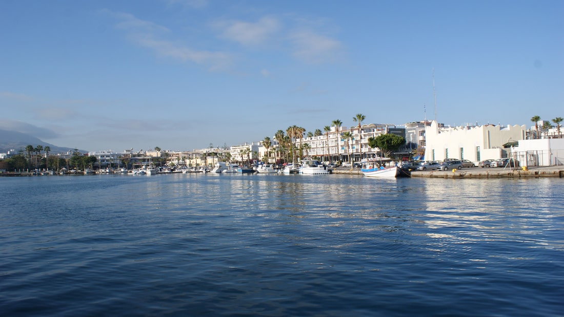 A Kos food tour starts at the harbour of Kos Town, lined with palm trees and white buildings