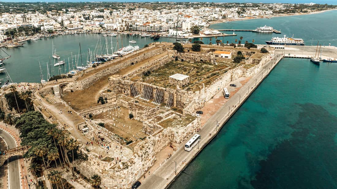 A Kos island tour starts at Kos harbour beside the walls of Neratzia castle above turquoise water
