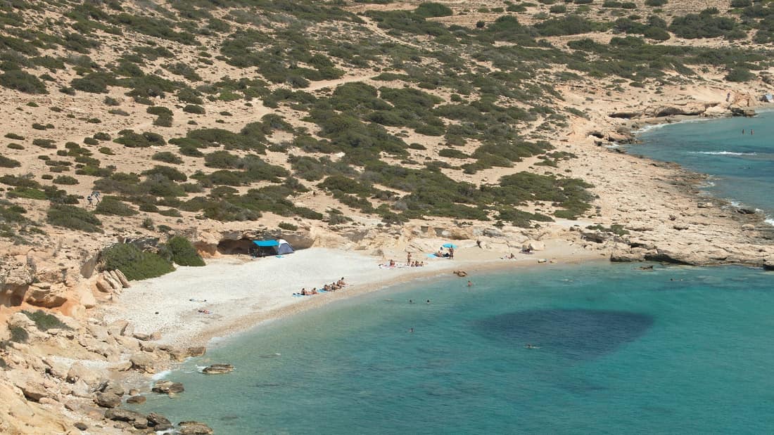 A Koufonisia cruise anchors off a pale pebble beach in the turquoise bay of Kato Koufonisi