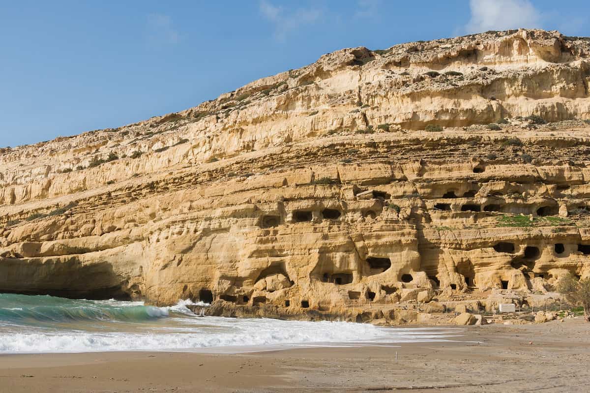 A Matala tour reaches the beach below the cliff full of carved caves