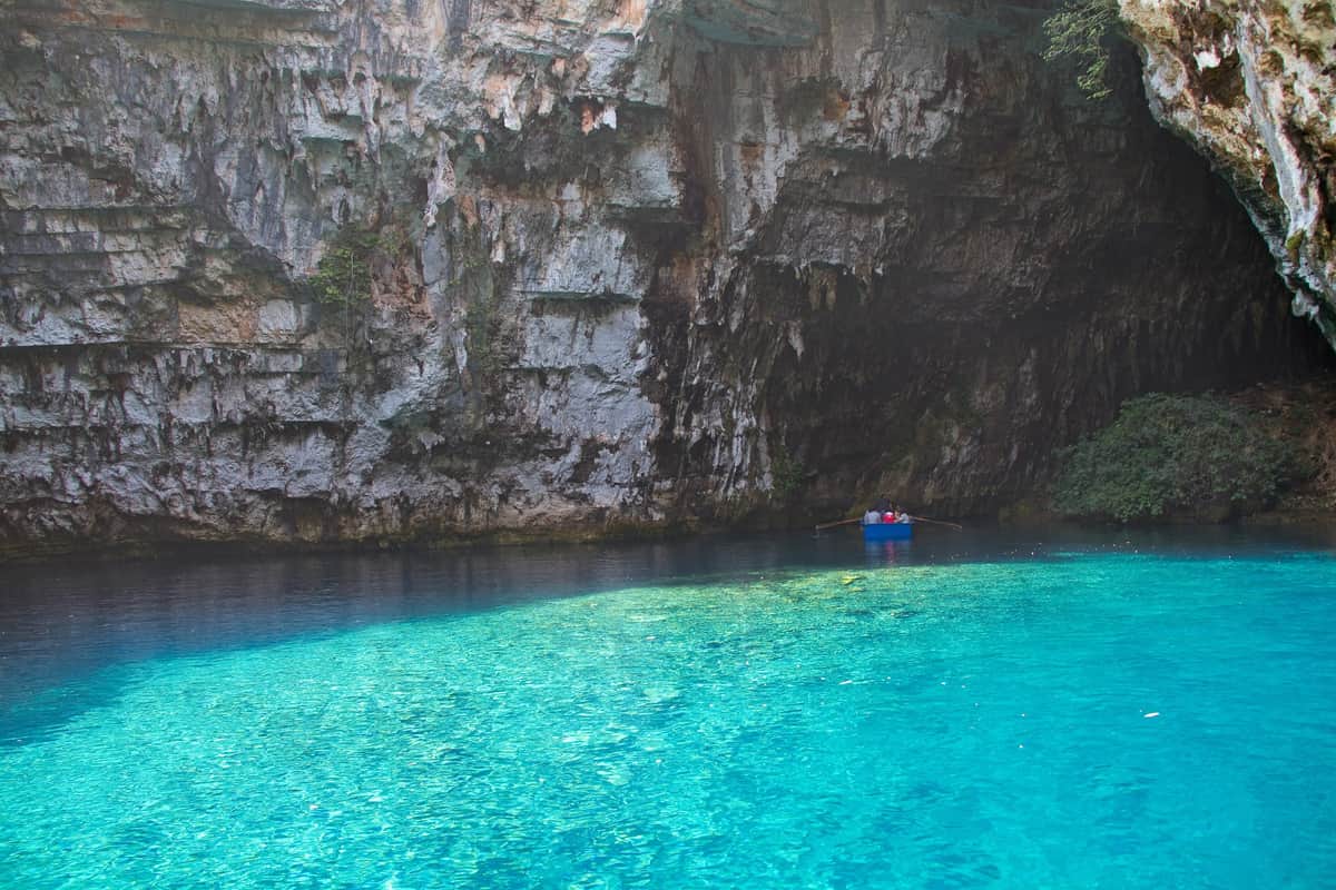 A Melissani cave tour rows across the turquoise lake under the limestone walls of the cave