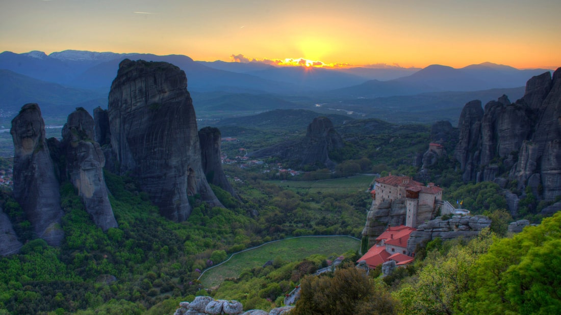 A Meteora sunset tour watches the sun go down over the rock pillars and a monastery on its rock