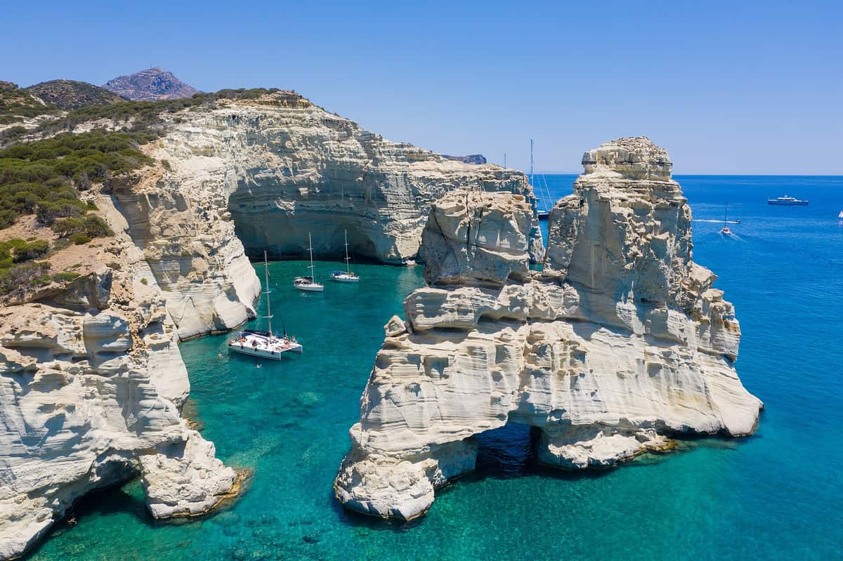 A Milos boat tour anchors among the rocks and sea caves of Kleftiko