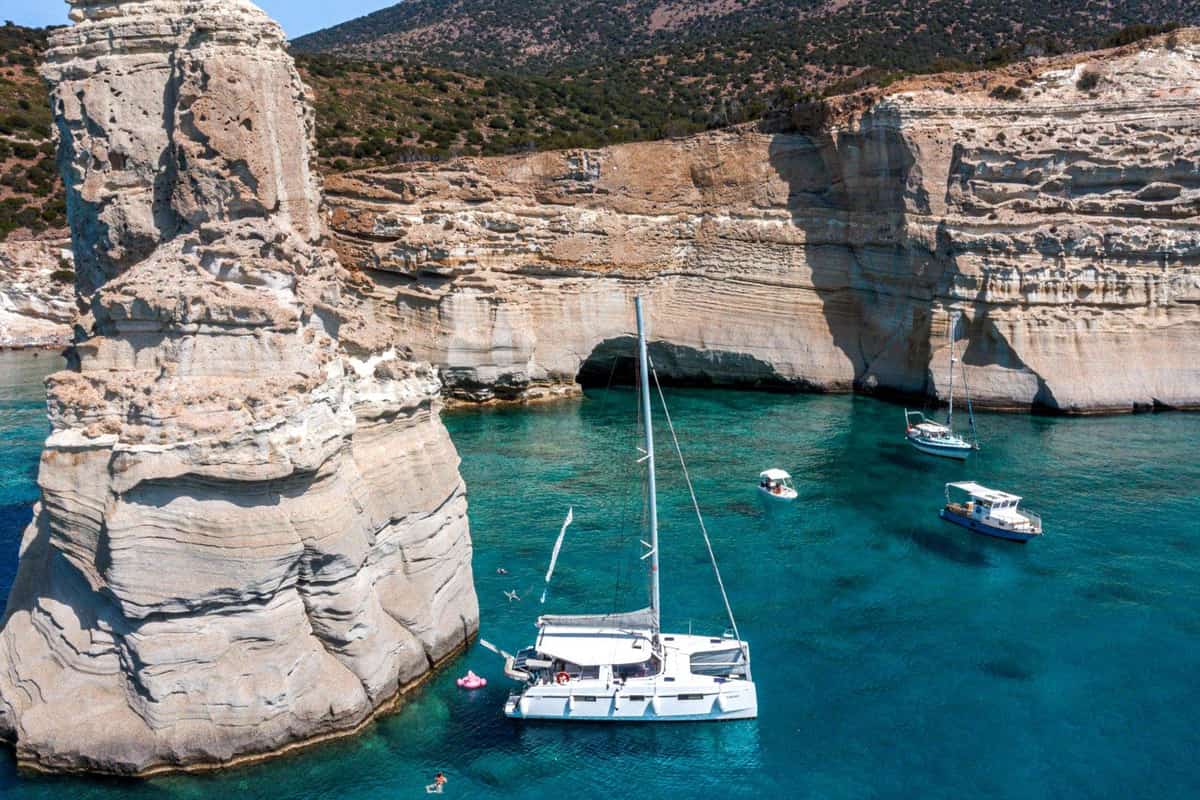 Milos boat trip boats anchored in turquoise water beside the white rock towers and sea caves of Kleftiko