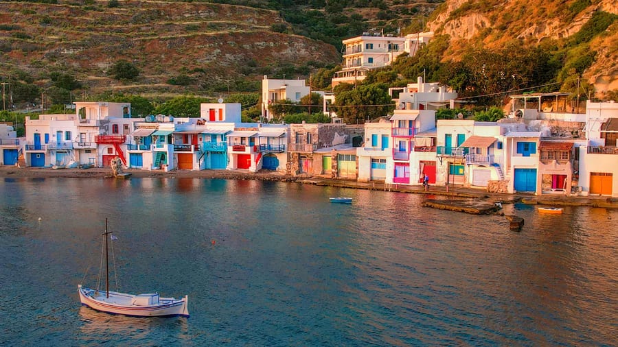 A small sailing boat in front of the colourful boathouses of Klima, seen on a Milos boat trip
