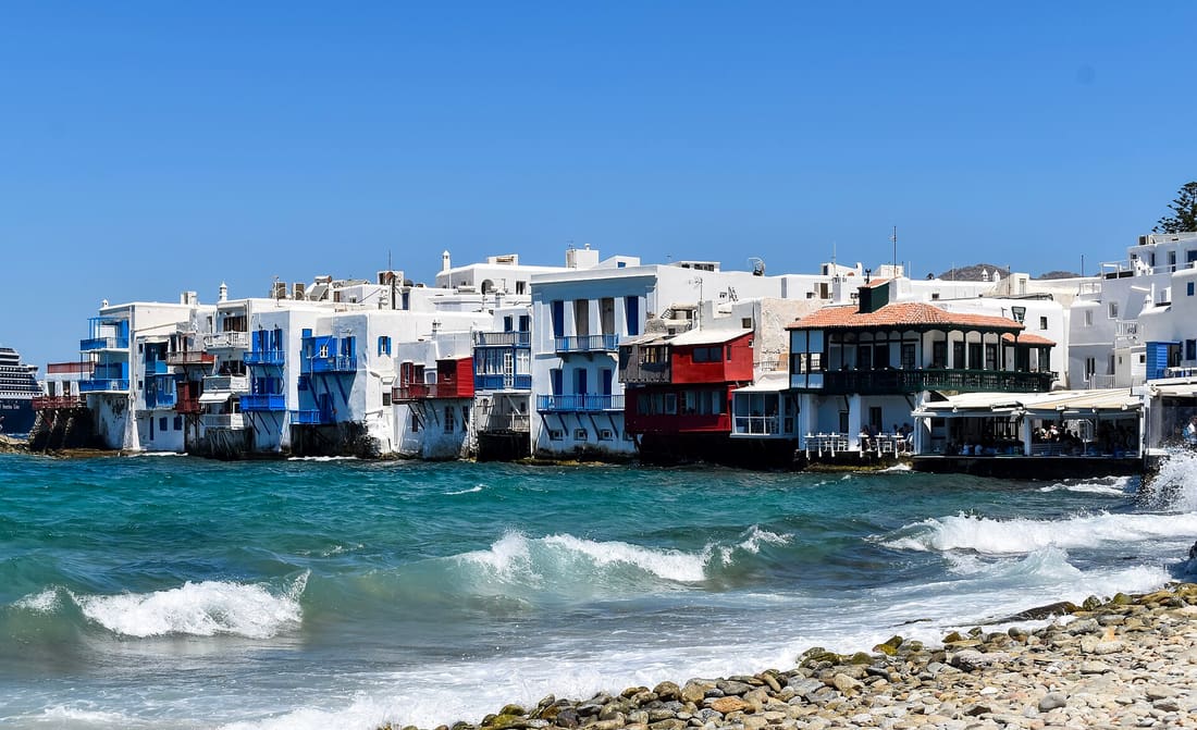 A Mykonos boat tour passes the houses of Little Venice built right over the waves