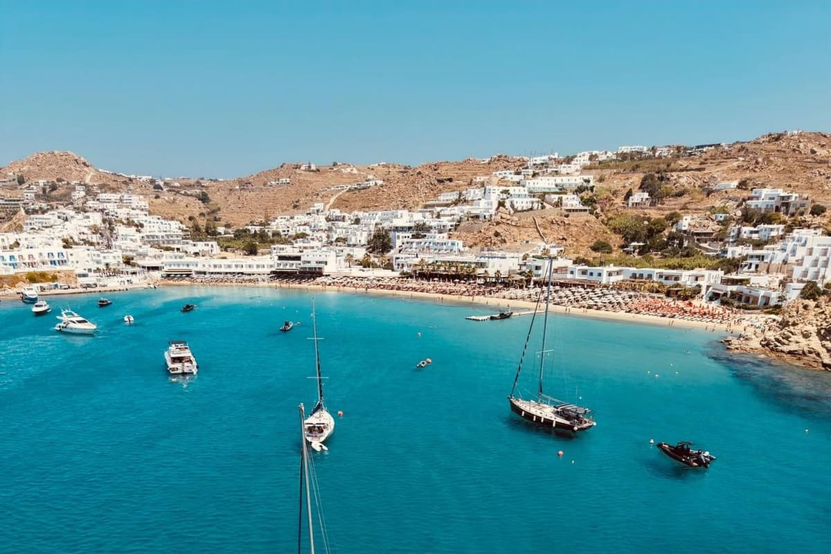 Mykonos boat trip sailboats and motor boats anchored in a turquoise south coast bay below white houses
