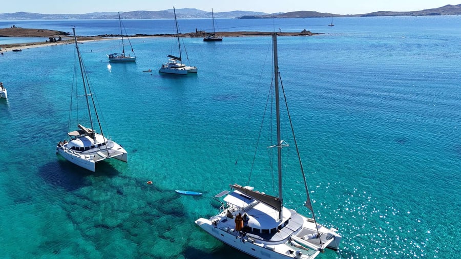 Sailing catamarans anchored in a turquoise bay off the Cyclades during a Mykonos catamaran cruise