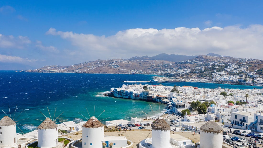 A Mykonos island tour stops at the windmills above Little Venice and the turquoise bay of Mykonos Town