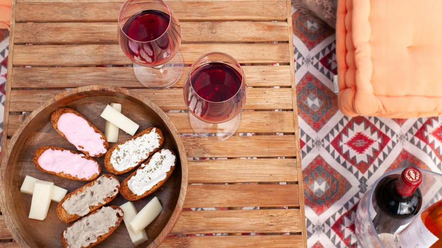 Two glasses of red wine beside a tray of bread with local cheese spreads on a Mykonos wine tour