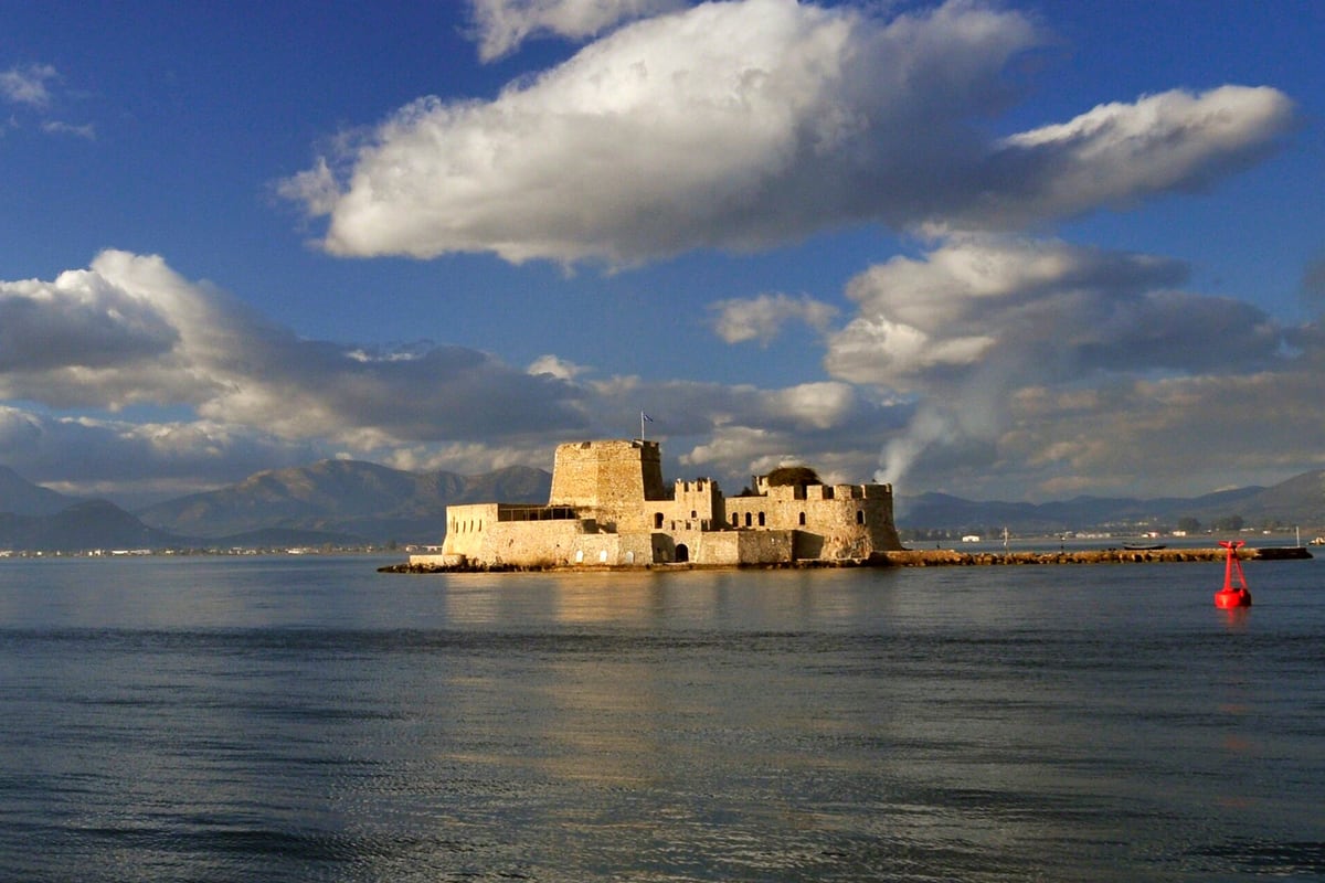 A Nafplio day trip looks across the bay to the sea castle of Bourtzi under a blue sky