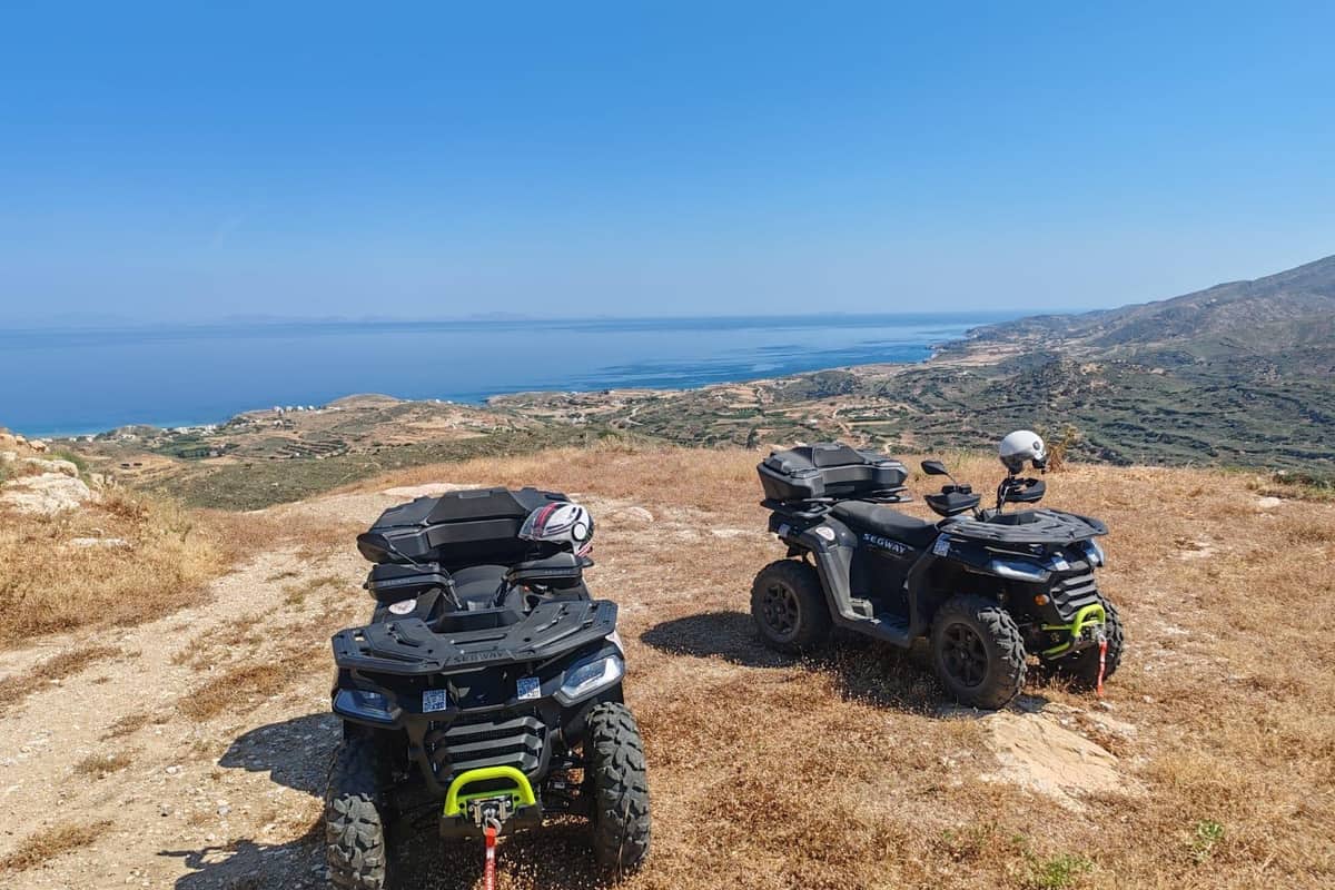 Naxos ATV tour with two black quads parked on a dry hilltop above the blue sea and the green coast of Naxos