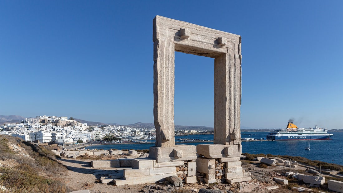 A Naxos boat trip sails past the marble Portara gate above the harbour of Naxos town