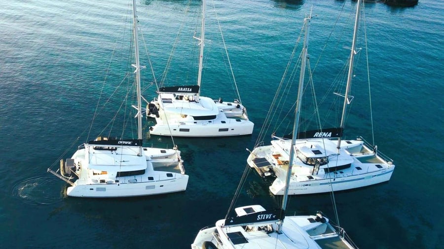 A Naxos catamaran swim stop, with four sailing catamarans at anchor side by side in deep blue water