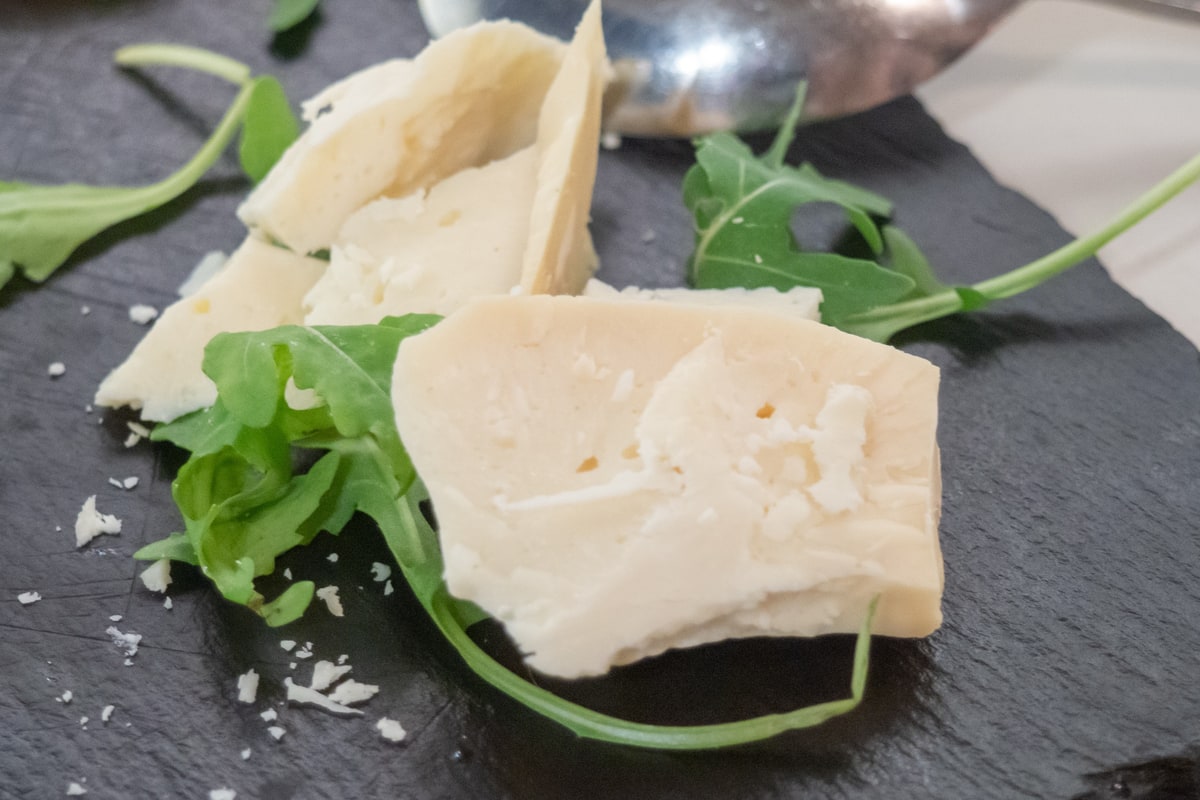 A Naxos food tour serves a tasting plate of arseniko, the hard local cheese of Naxos, with rocket leaves on slate