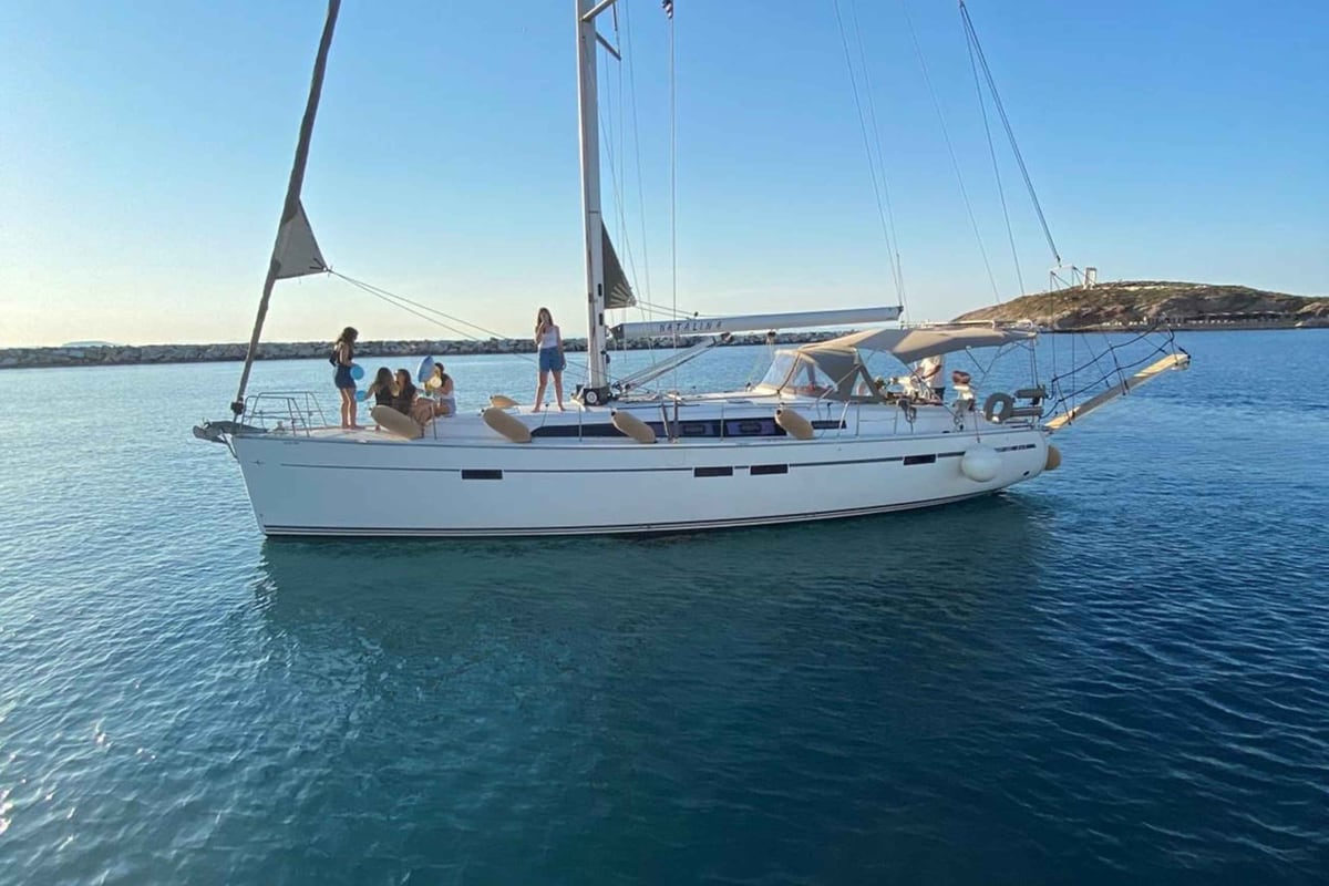 A Naxos sailing trip glides over calm blue water on a sailing yacht with guests relaxing on deck