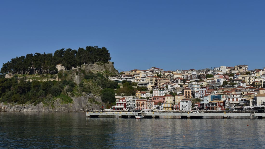 A Parga boat trip sails past the wooded castle hill and the colourful houses of Parga above the harbour