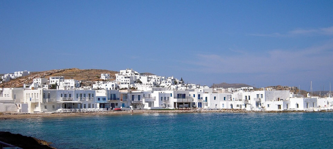 A Paros boat trip passes the white houses of Naoussa above the turquoise bay