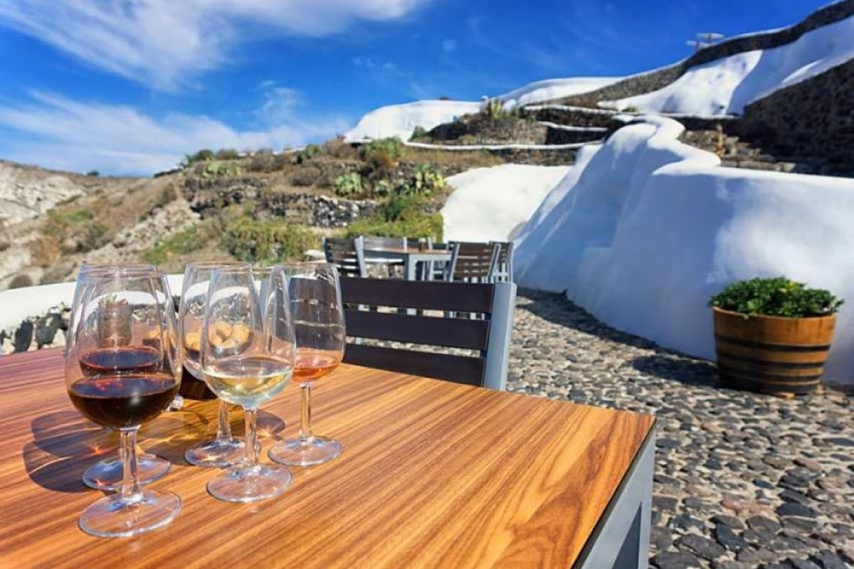 Paros wine tour tasting flight of red, white and rose wine on a wooden table by whitewashed island walls