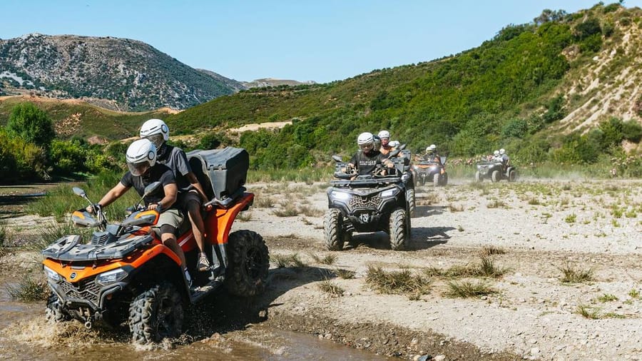 Riders on quads splash across a stream in the hills behind Rethymno on a Rethymno ATV tour