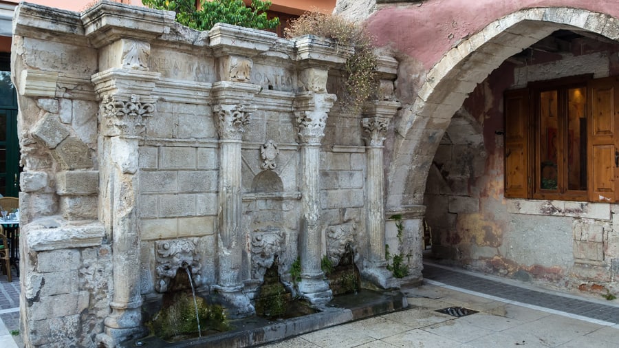 A Rethymno food tour walks past the Rimondi Fountain, the Venetian fountain with lion-head spouts in the old town
