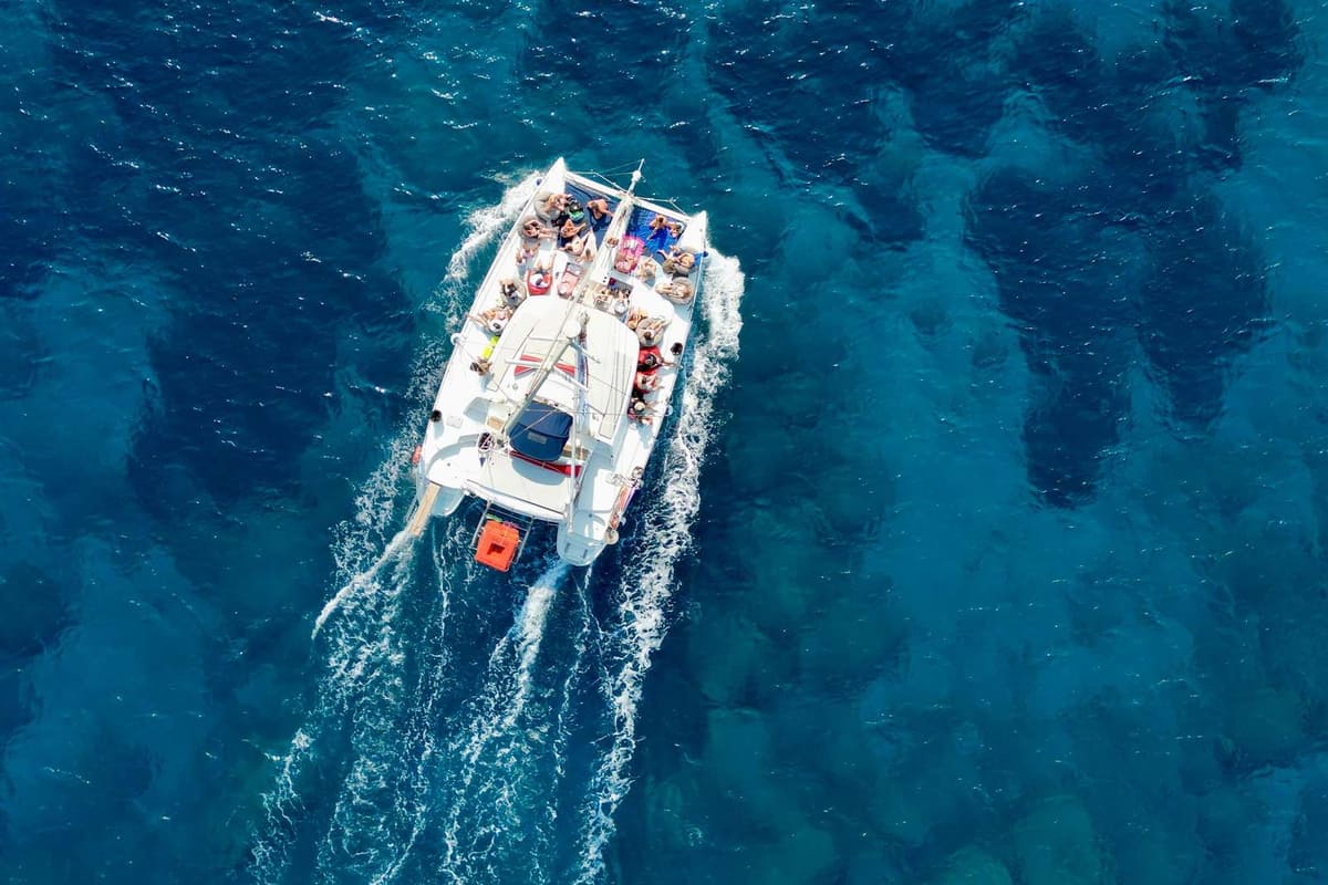 Rhodes catamaran cruise seen from above, a sailing catamaran with passengers on deck crossing deep blue water