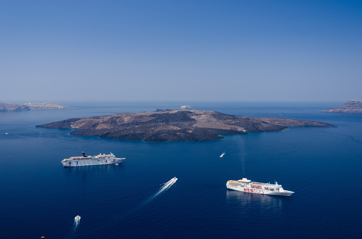 A Santorini catamaran cruise sails the caldera of Santorini below Fira
