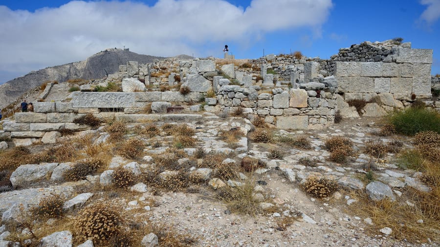 A Santorini hiking tour reaches the stone ruins of Ancient Thera on the ridge of Mesa Vouno