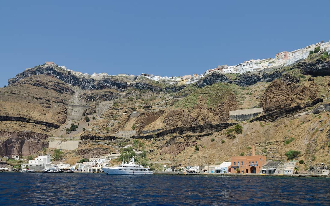 A Santorini private tour looks up from the sea at Fira on top of the caldera cliffs
