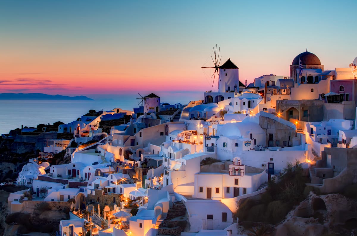 A Santorini sunset tour ends in Oia as the sun sets behind the windmill and blue domes