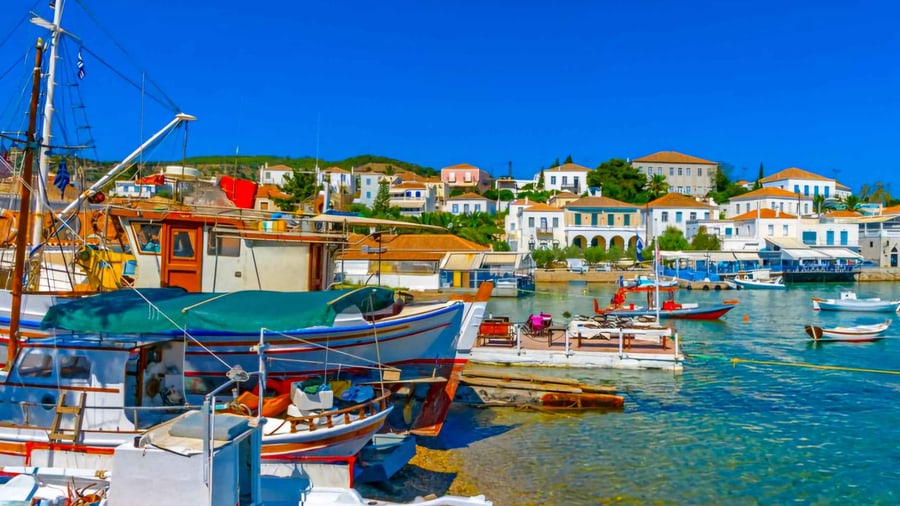 A Spetses day trip passes wooden caiques moored below the white and ochre houses of Spetses town