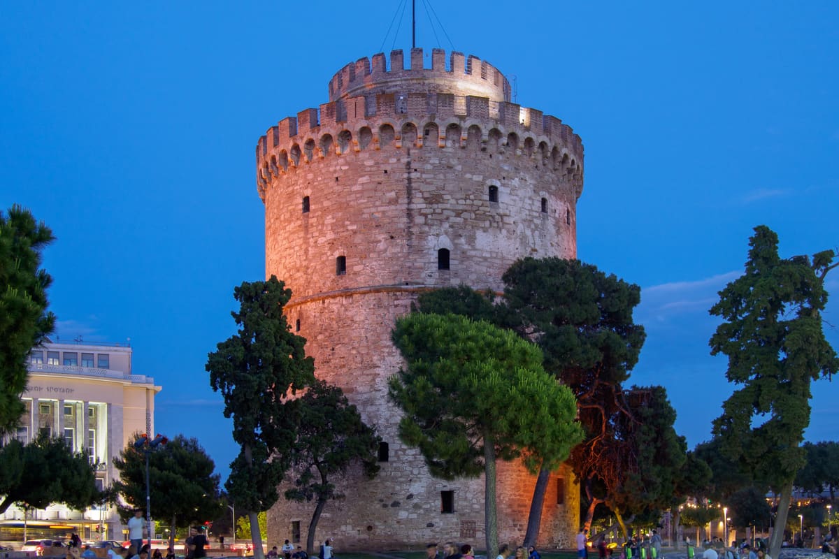 The White Tower of Thessaloniki lit up at dusk on the waterfront, the landmark of a Thessaloniki sunset cruise